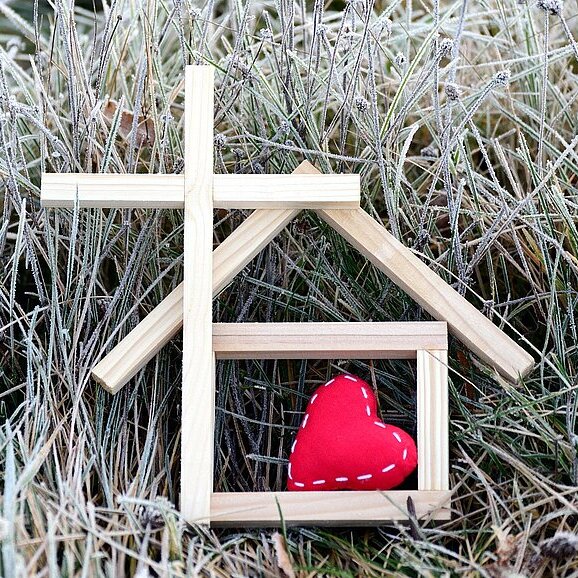 Kirchengebäude aus Holzklötzen mit einem roten Herz auf einer Wiese